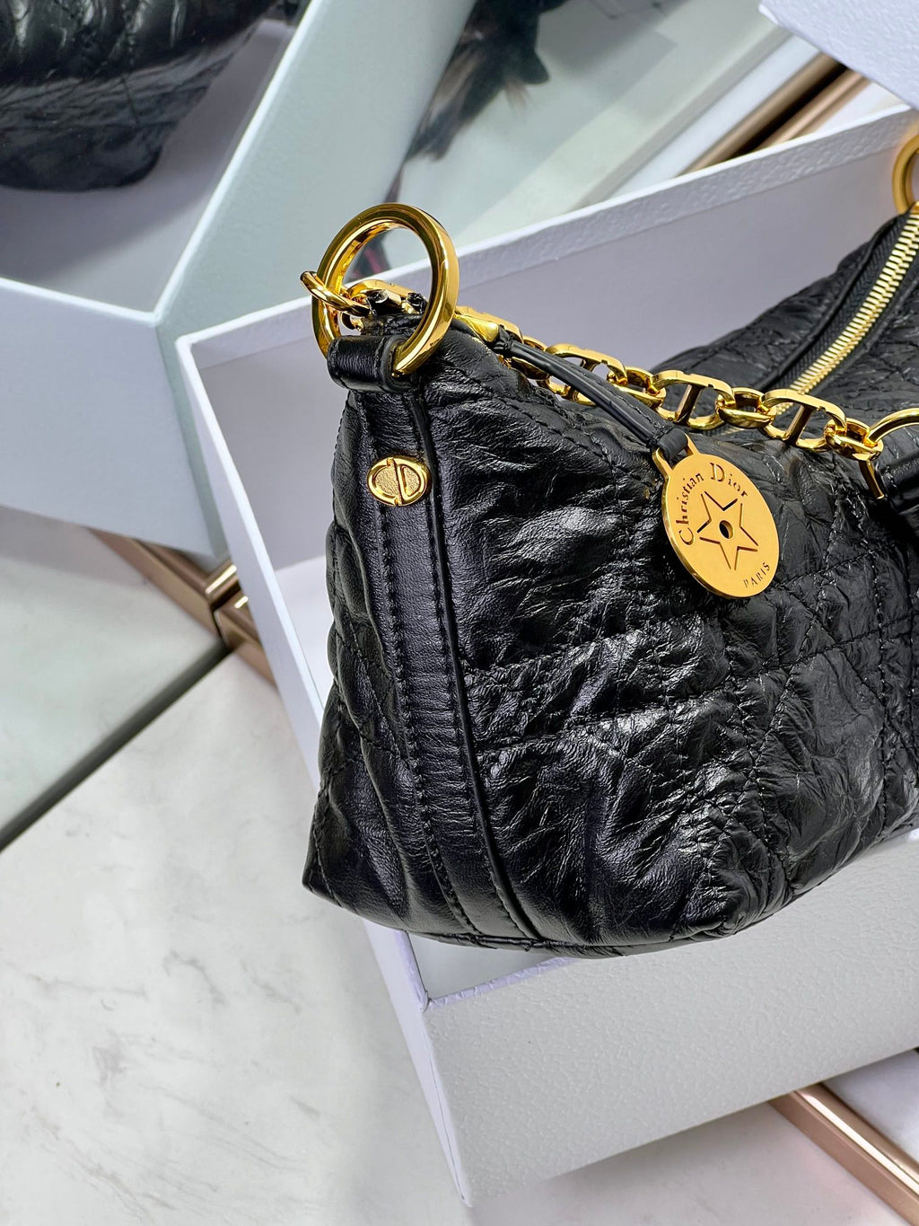 Dior black mini hobo bag with gold chain handle and round logo charm.