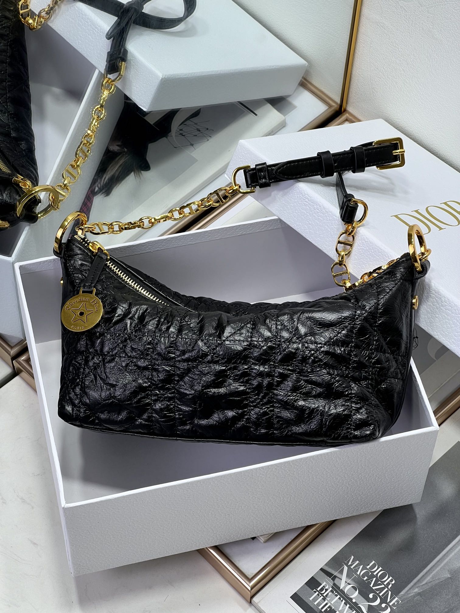 Dior black hobo bag with gold chain strap and zipper pocket detailing.