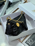 Dior black hobo bag with gold chain strap, zip-top, and logo charm tag.