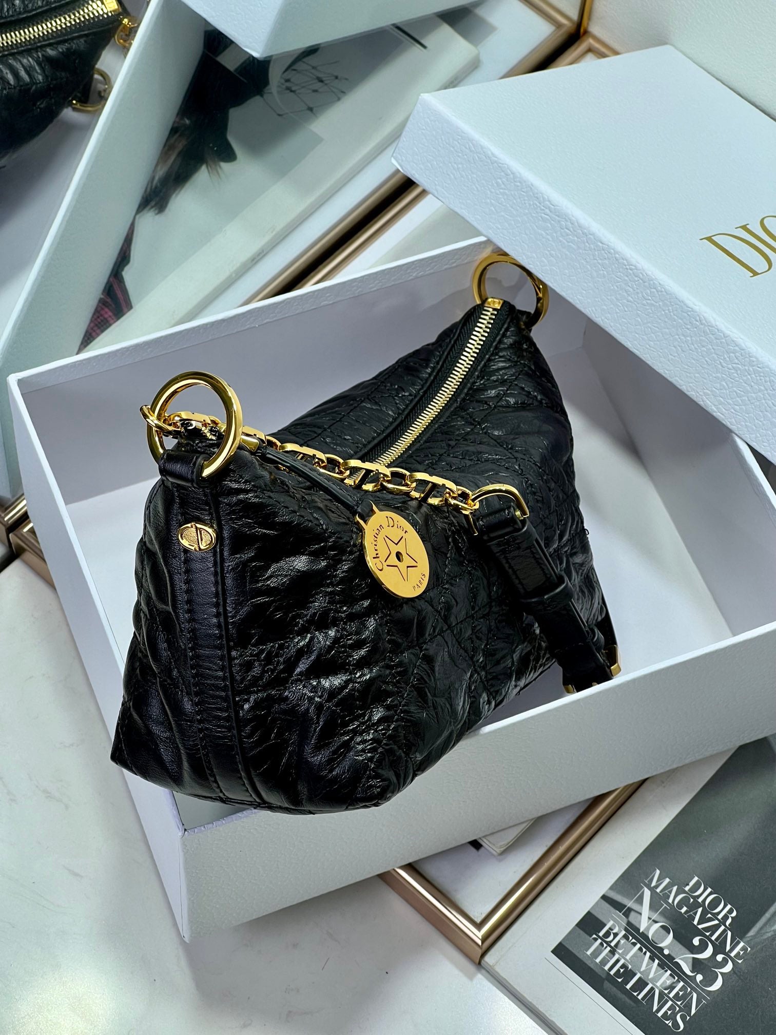 Dior black hobo bag with gold chain strap, zip-top, and logo charm tag.