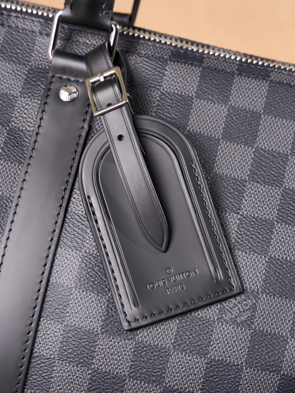 Men's Louis Vuitton logo leather luggage tag on checkered duffel bag