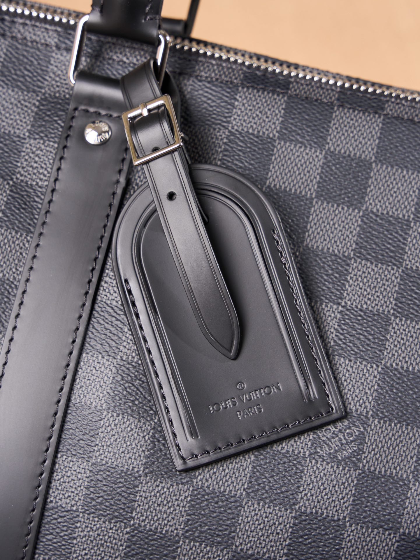Men's Louis Vuitton logo leather luggage tag on checkered duffel bag