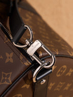 Silver-tone clasp and strap attachment on monogram duffel bag, black leather