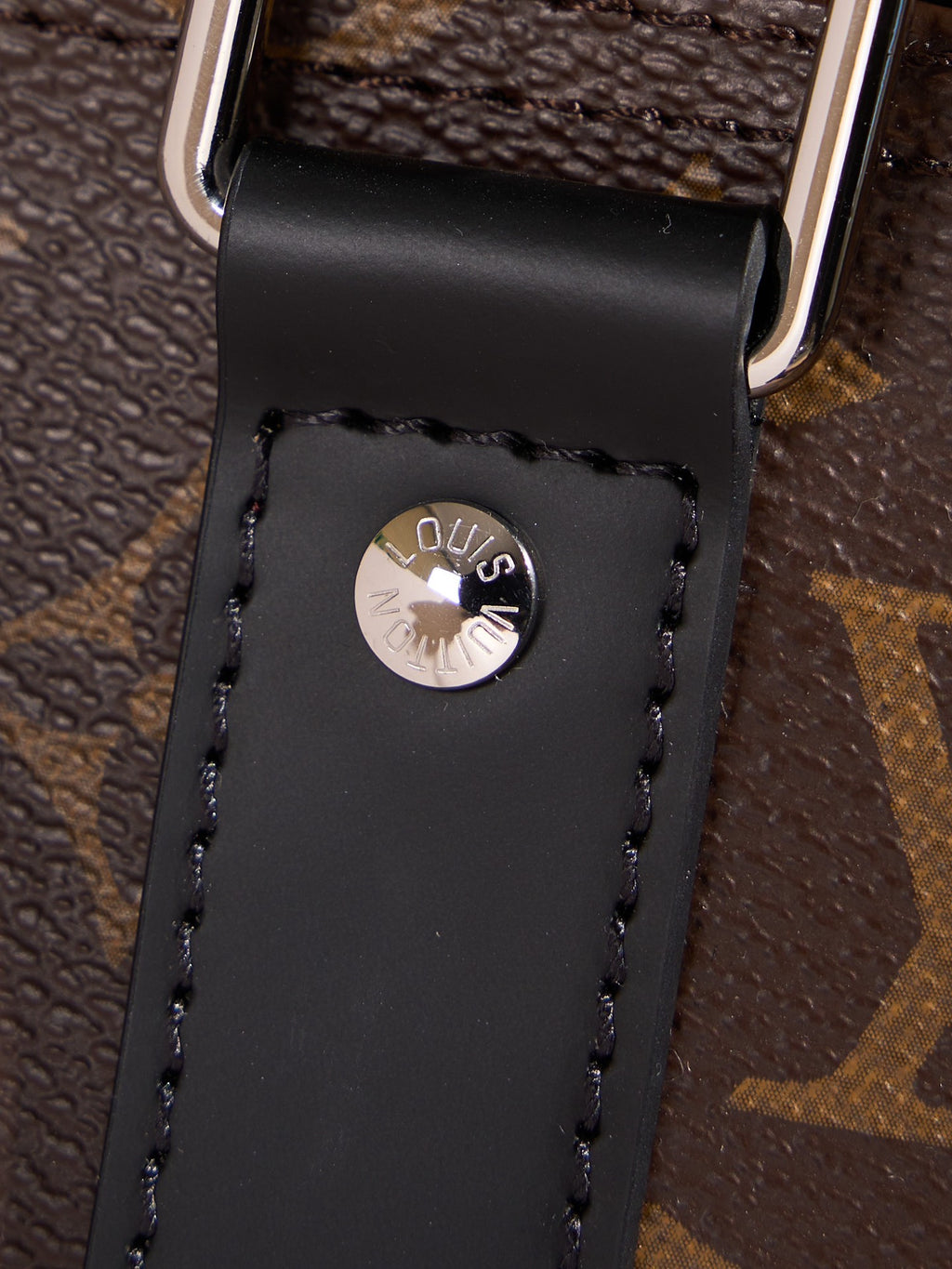 Black leather luggage tag with LV emblem on monogram duffel bag strap