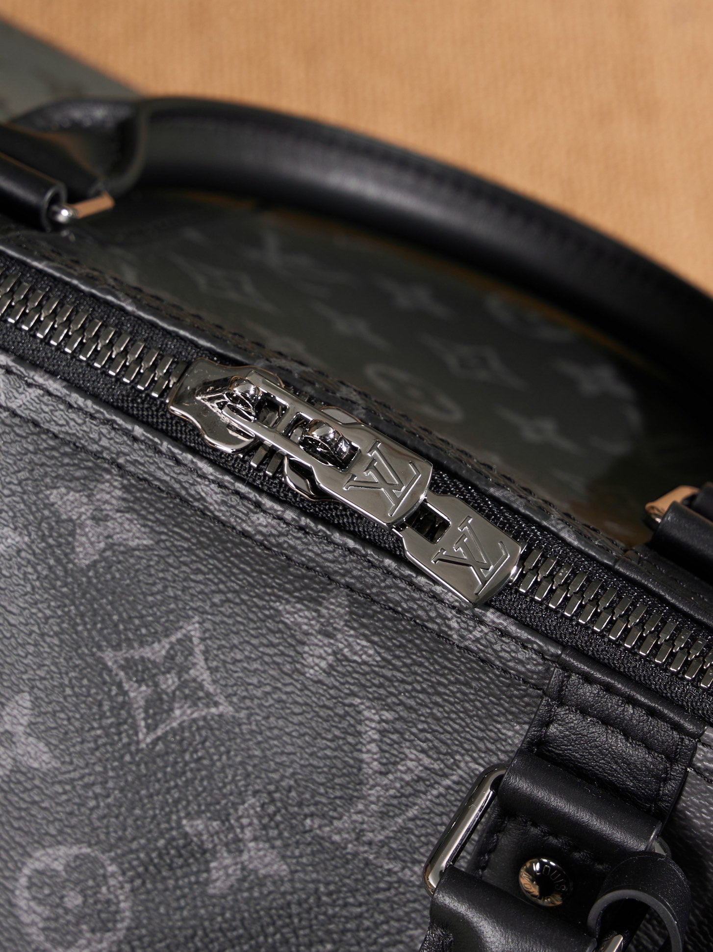 Louis Vuitton duffel bag zipper pull on black leather trim with monogram pattern
