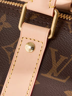 Monogram duffel bag strap end with light tan leather tab and gold logo rivet