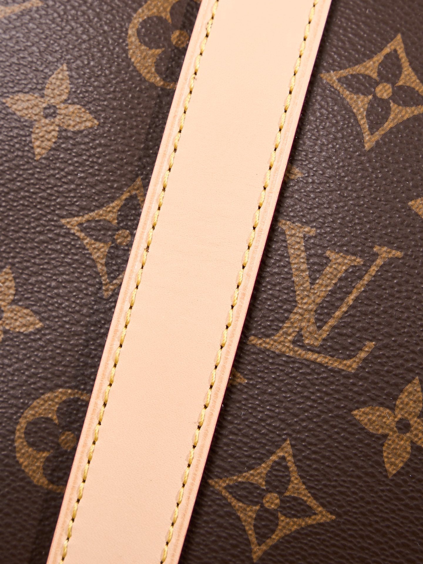 Light tan leather strap on monogram duffel bag, stitched edges