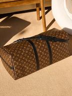 Monogram duffel bag with long zipper and black leather piping, side angle