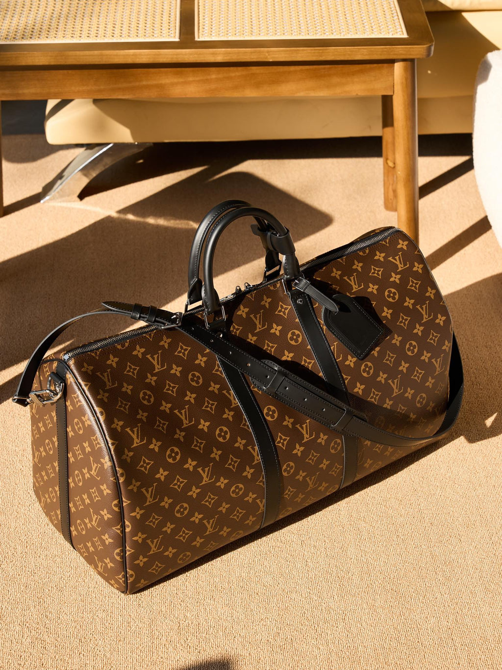 Monogram duffel bag with black leather trim, side view with zipper pull