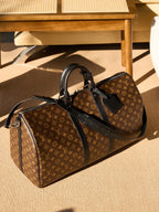 Monogram duffel bag with black leather trim, side view with zipper pull