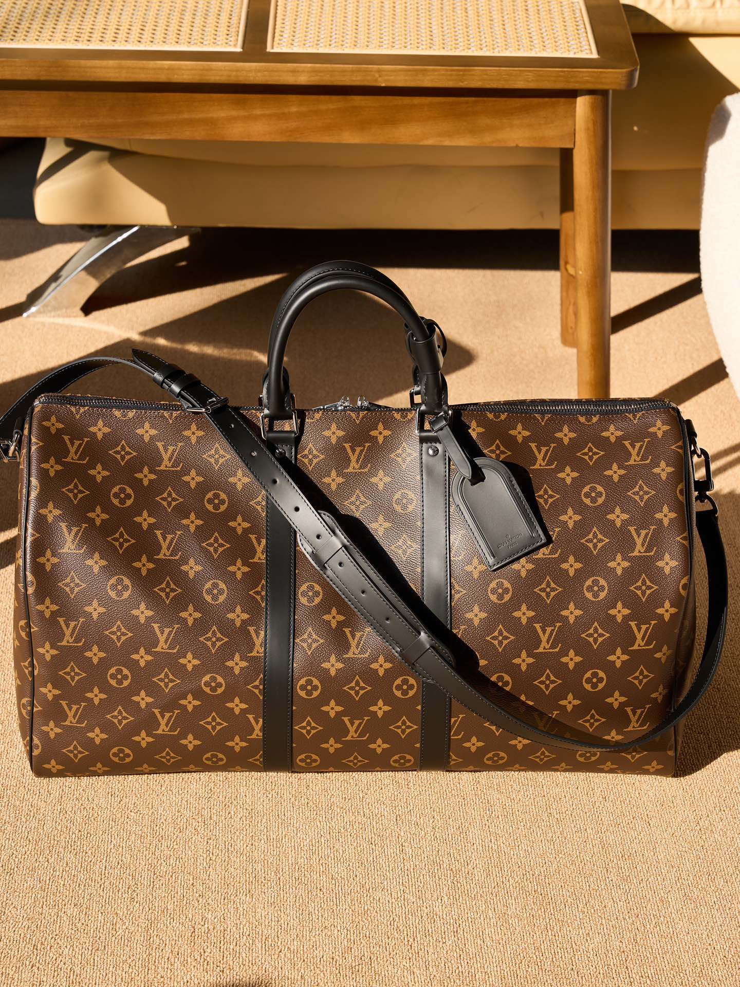 Monogram duffel bag with black crossbody strap and top handles, front view