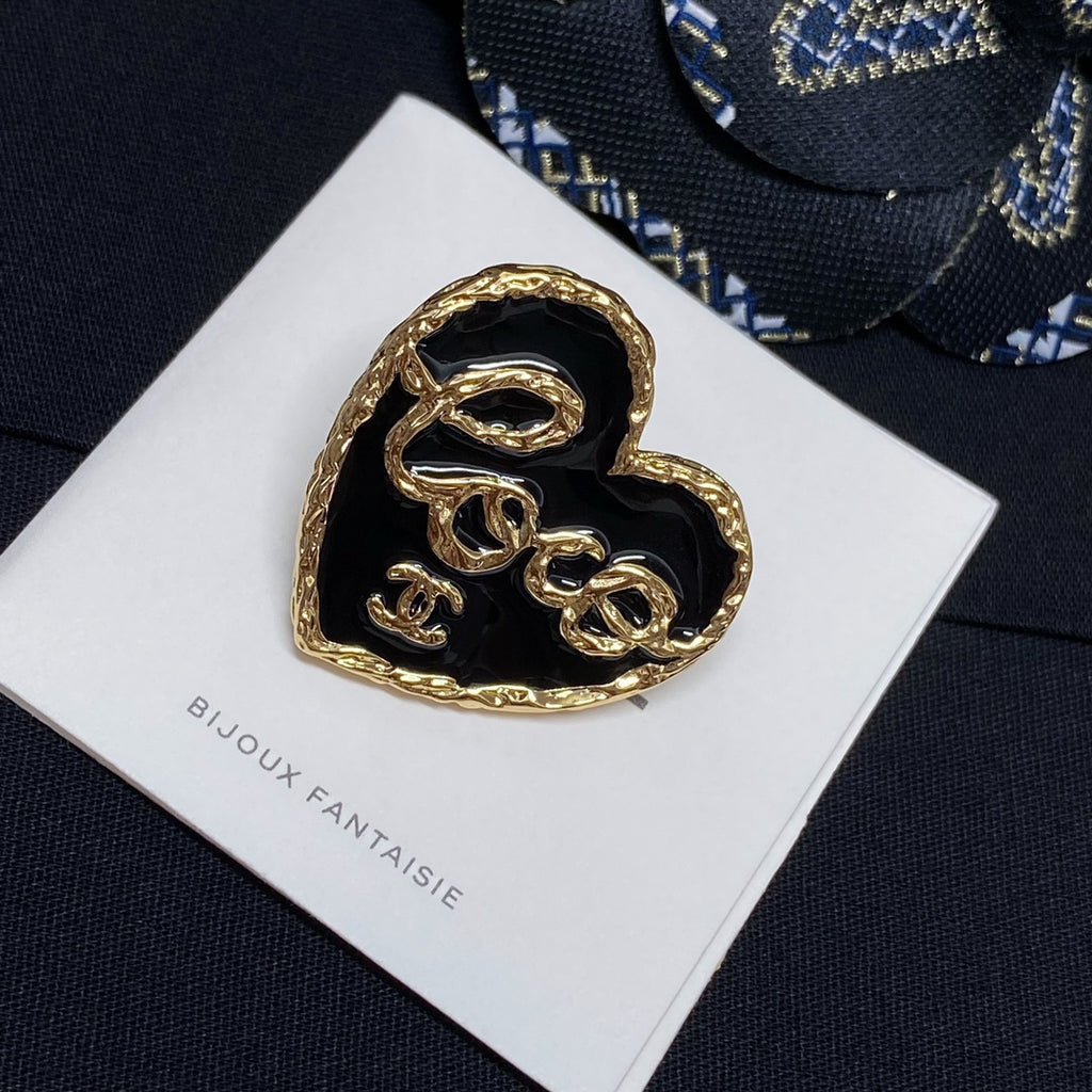 Heart-shaped gold-tone brooch with black enamel center on white Bijoux Fantaisie card