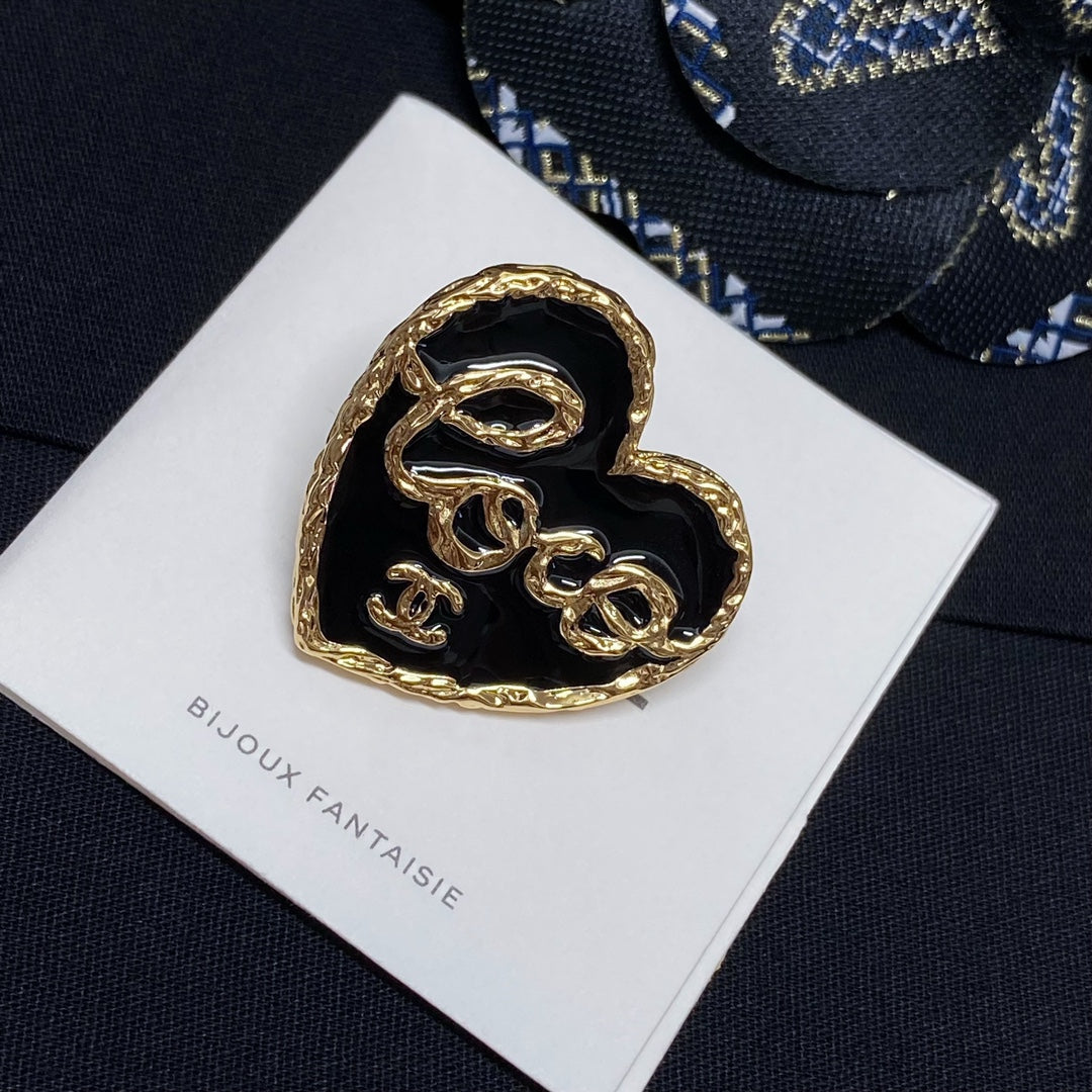Heart-shaped gold-tone brooch with black enamel center on white Bijoux Fantaisie card