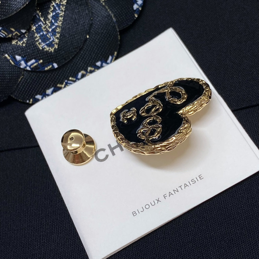 Heart-shaped gold-tone brooch with black enamel, shown with small round stud backing