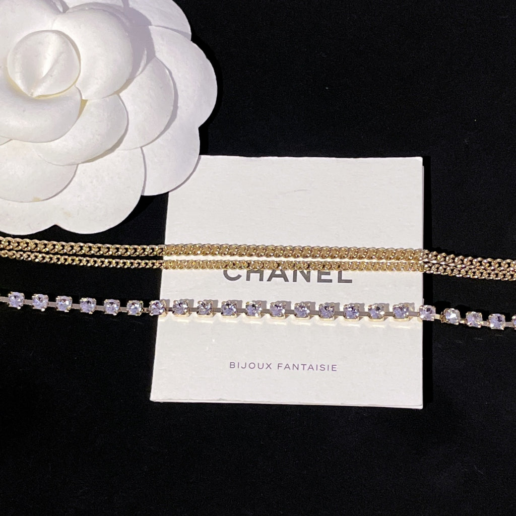 Layered gold chain and purple crystal tennis-style necklace on display card
