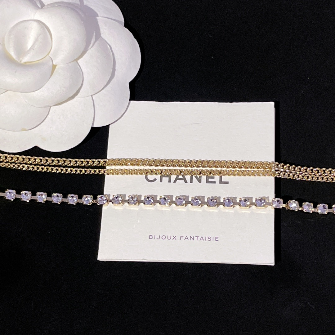 Layered gold chain and purple crystal tennis-style necklace on display card