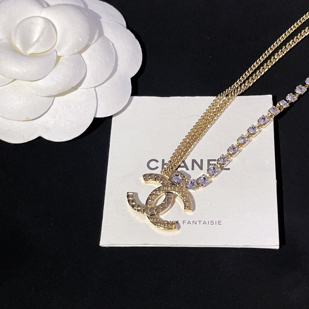 Gold-tone pendant necklace with rhinestone details on display card