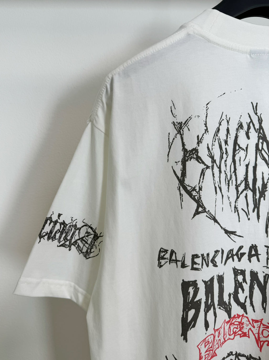 White T-shirt sleeve and partial back graphic in black lettering