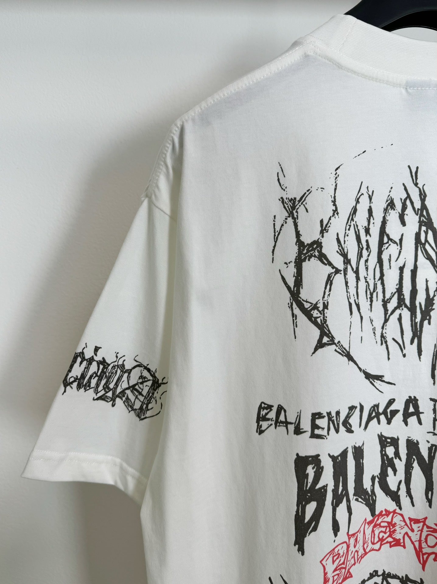 White T-shirt sleeve and partial back graphic in black lettering
