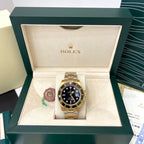 Rolex watch in open display box, black dial and gold-tone bracelet
