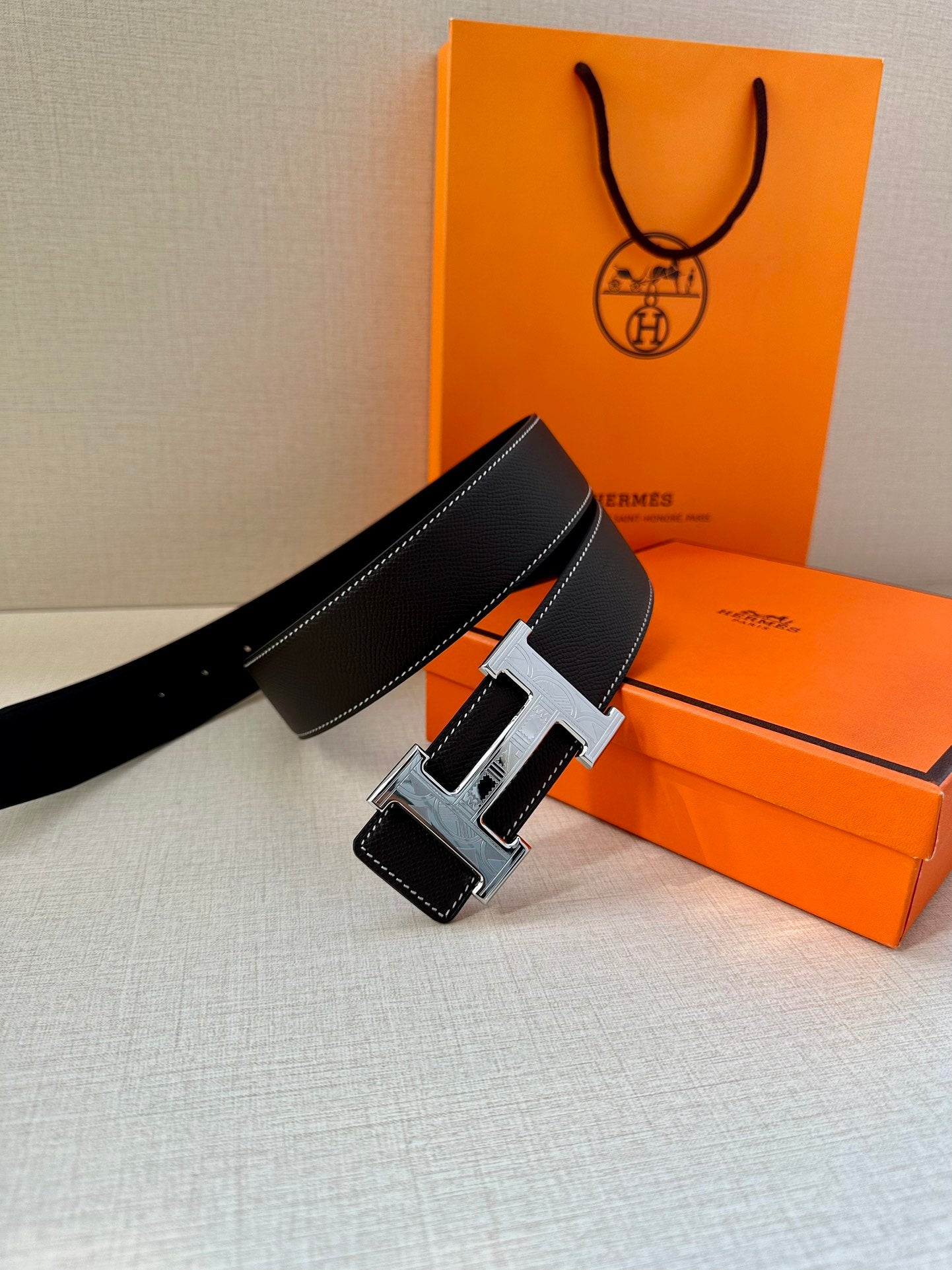 Hermes leather belt, angled view of dark strap with silver buckle and stitched trim
