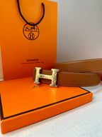 Tan leather belt with metal H buckle, laid flat for display