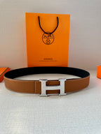 Tan leather belt with metal H buckle, full view on display