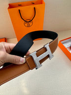 Tan leather belt with metal H buckle and black underside detail
