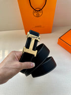 Hermes belt detail, dark navy leather strap with silver H buckle and rectangular frame