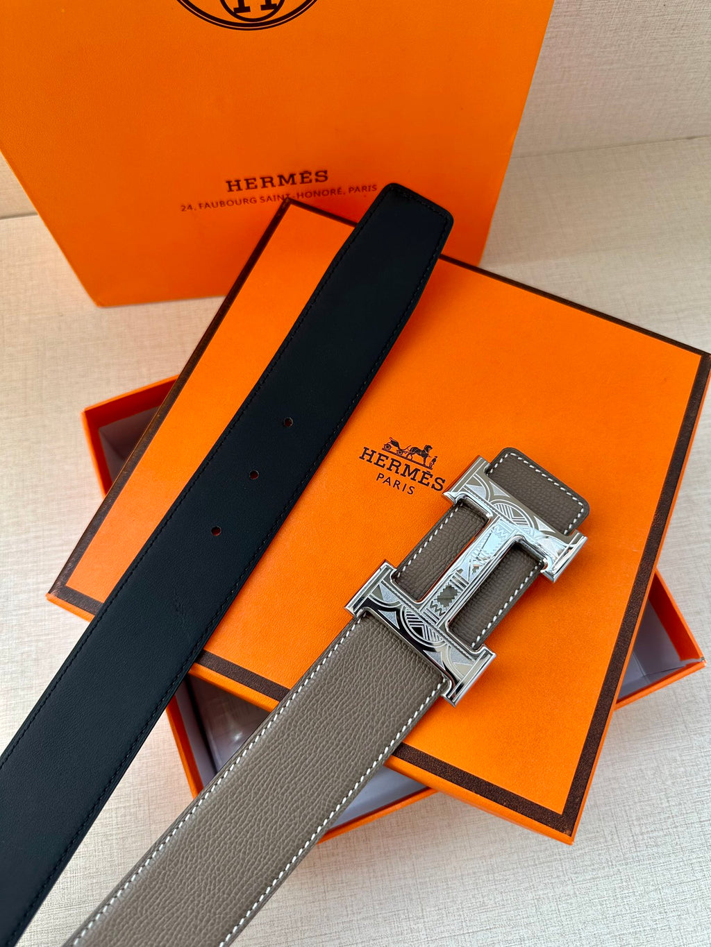 Leather belt with textured gray strap, black strap end, and silver-tone buckle.