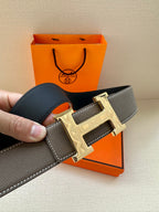 Leather belt with textured gray strap and gold-tone buckle with pin holes.