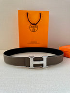 Leather belt with textured gray strap and silver-tone H buckle, laid flat.