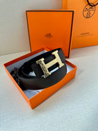 Black leather belt with silver-tone H buckle, laid on display surface.
