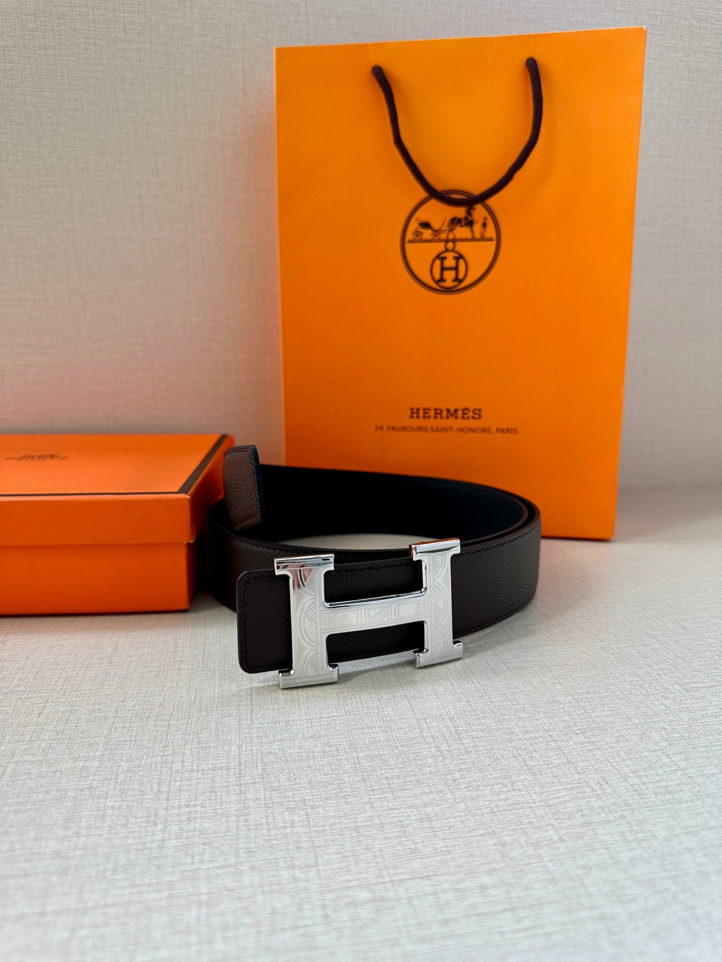 Black leather belt with silver-tone H buckle, laid flat.