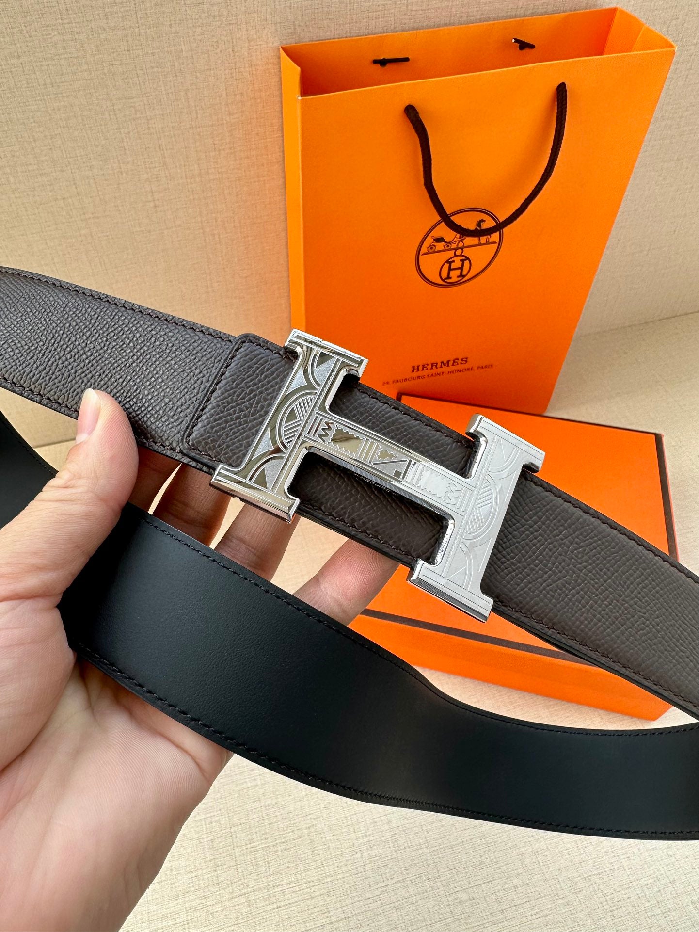 Black leather belt with silver-tone H buckle, belt end and buckle close-up.