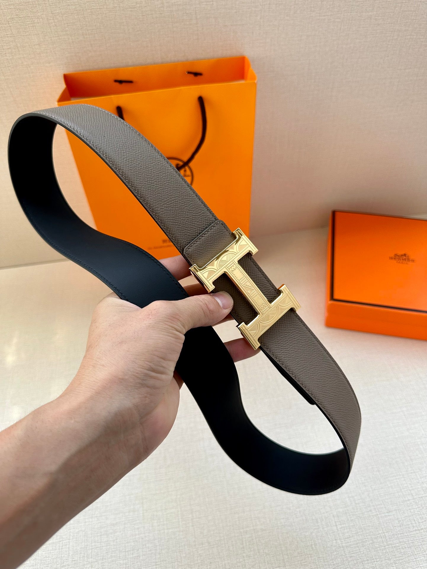 Gray leather belt with gold-tone H buckle and smooth strap edge