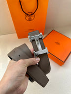 Gray leather belt close-up with silver-tone H buckle and stitching