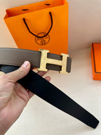 Gray leather belt with gold-tone H buckle and black lining on strap
