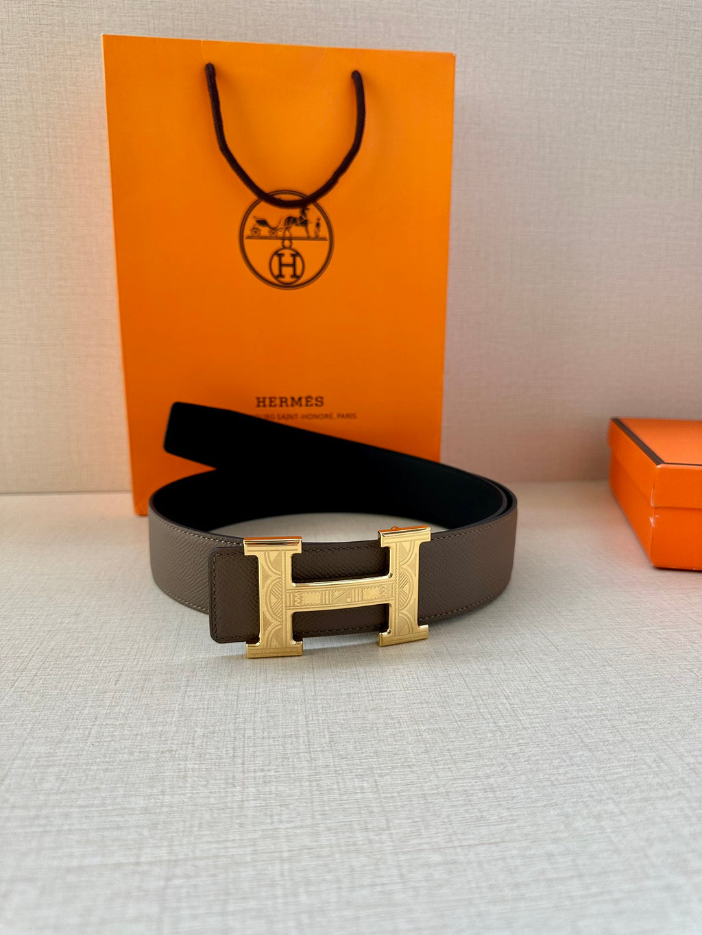 Gray leather belt with gold-tone H buckle, flat and centered