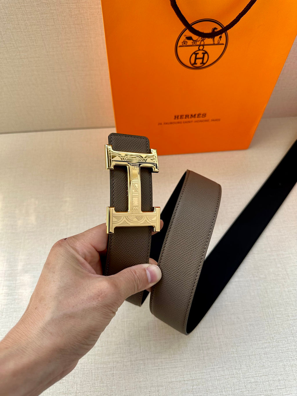 Gray leather belt with gold-tone H buckle and textured surface