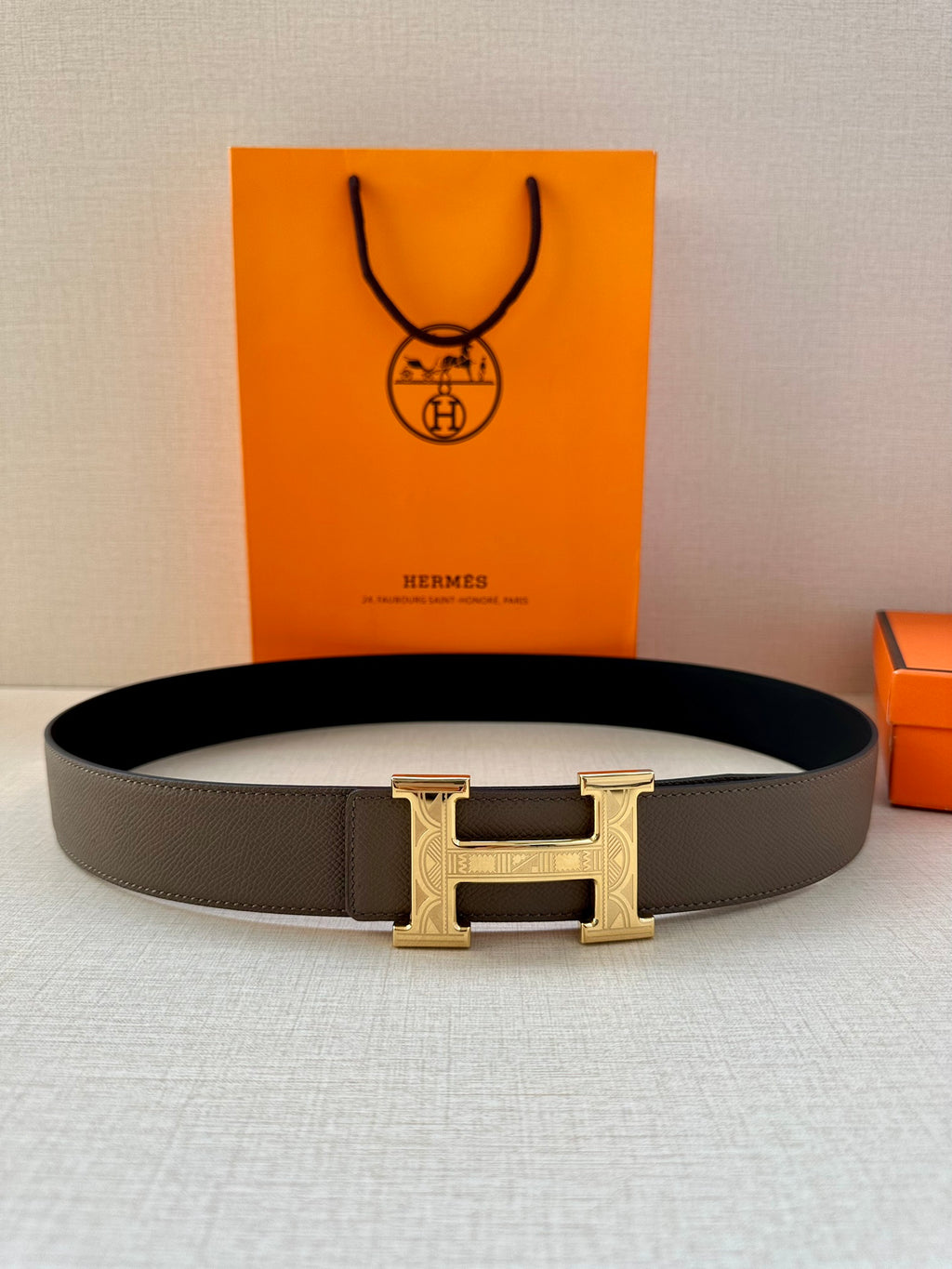 Gray leather belt with gold-tone H buckle, shown straight-on