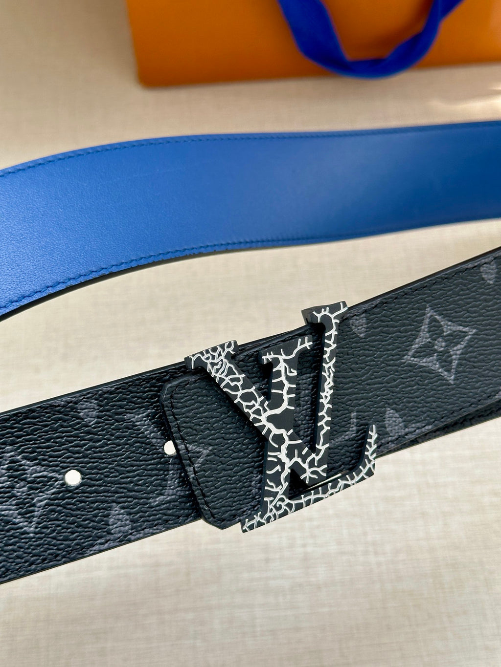 Louis Vuitton belt close-up: dark blue monogram strap with patterned center and buckle.