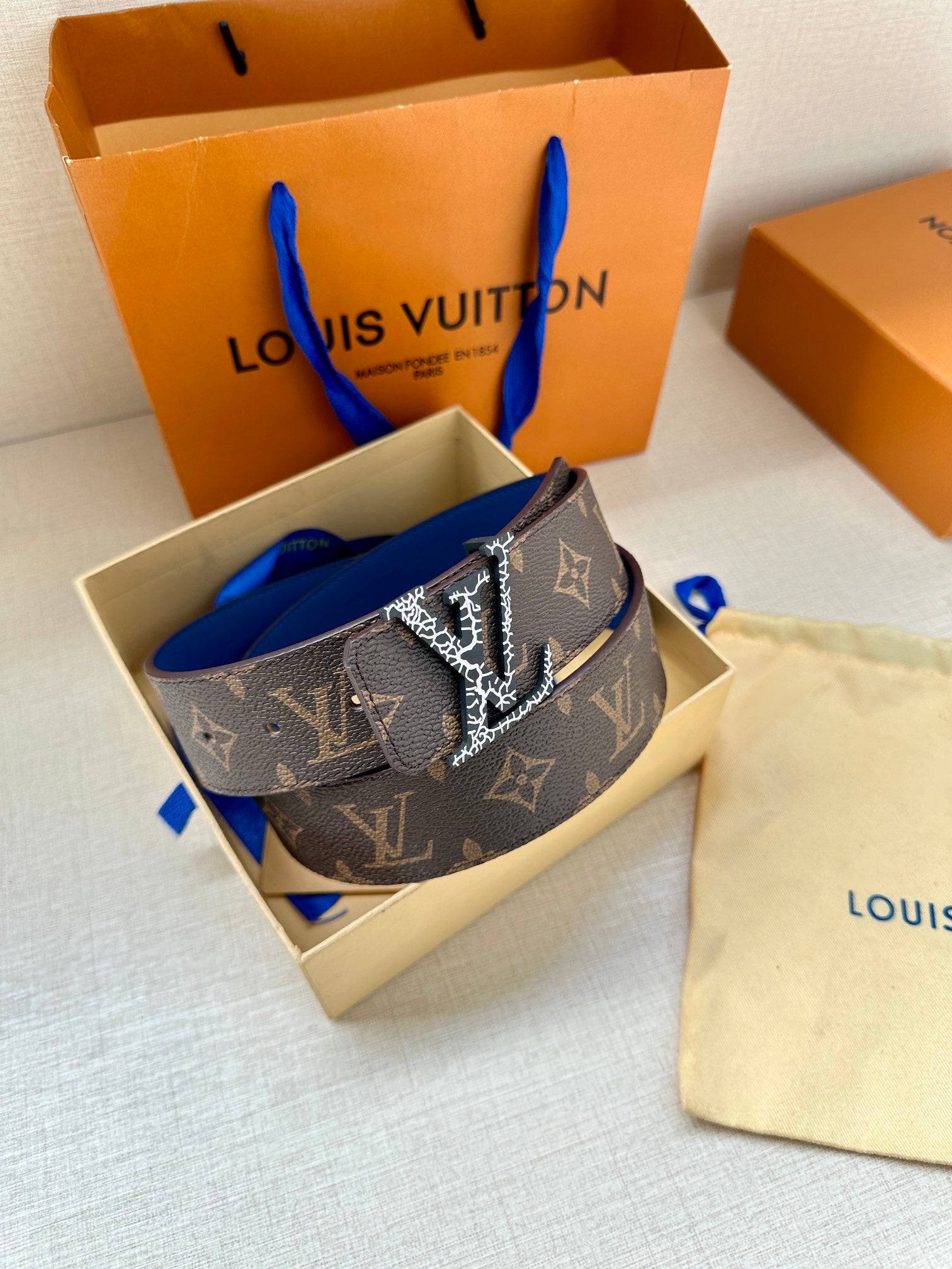 Monogram canvas belt with LV buckle, dark brown strap and blue edge detail