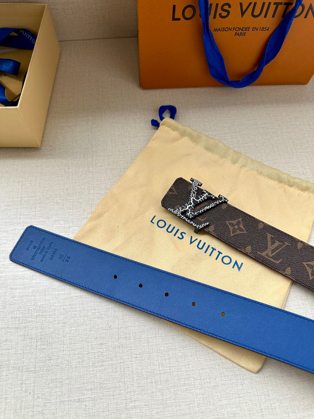 Monogram canvas belt with LV buckle, dark brown strap and blue backing