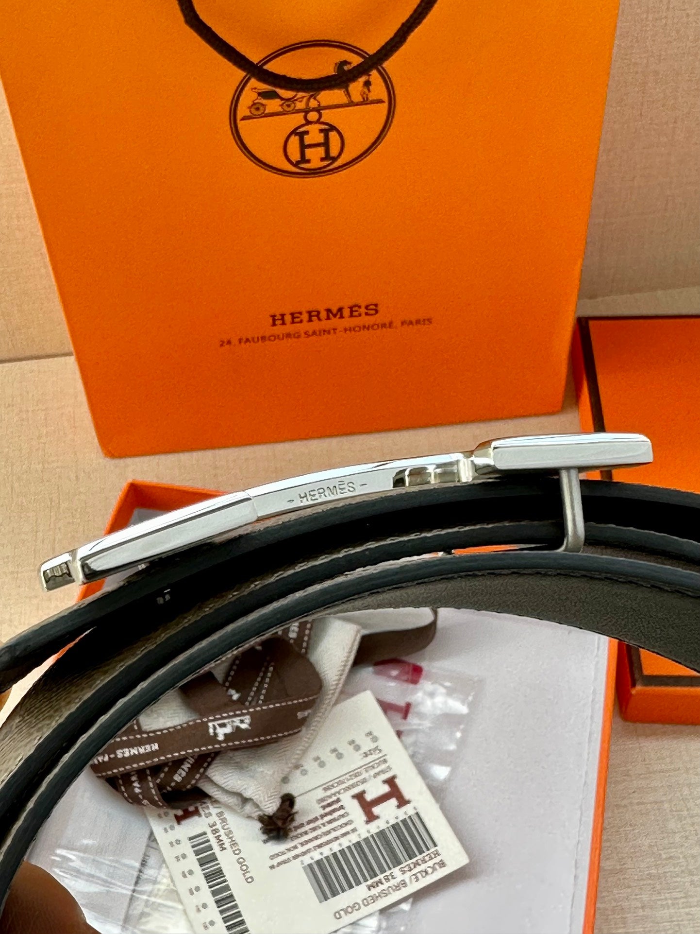 Gray leather belt with silver-tone H buckle and attached tags