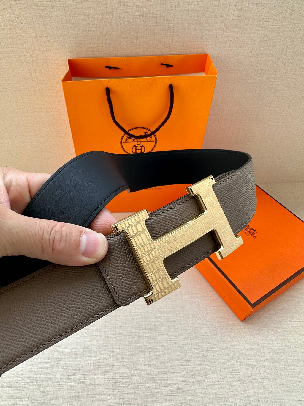 Gray leather belt with silver-tone H buckle, close-up angled view