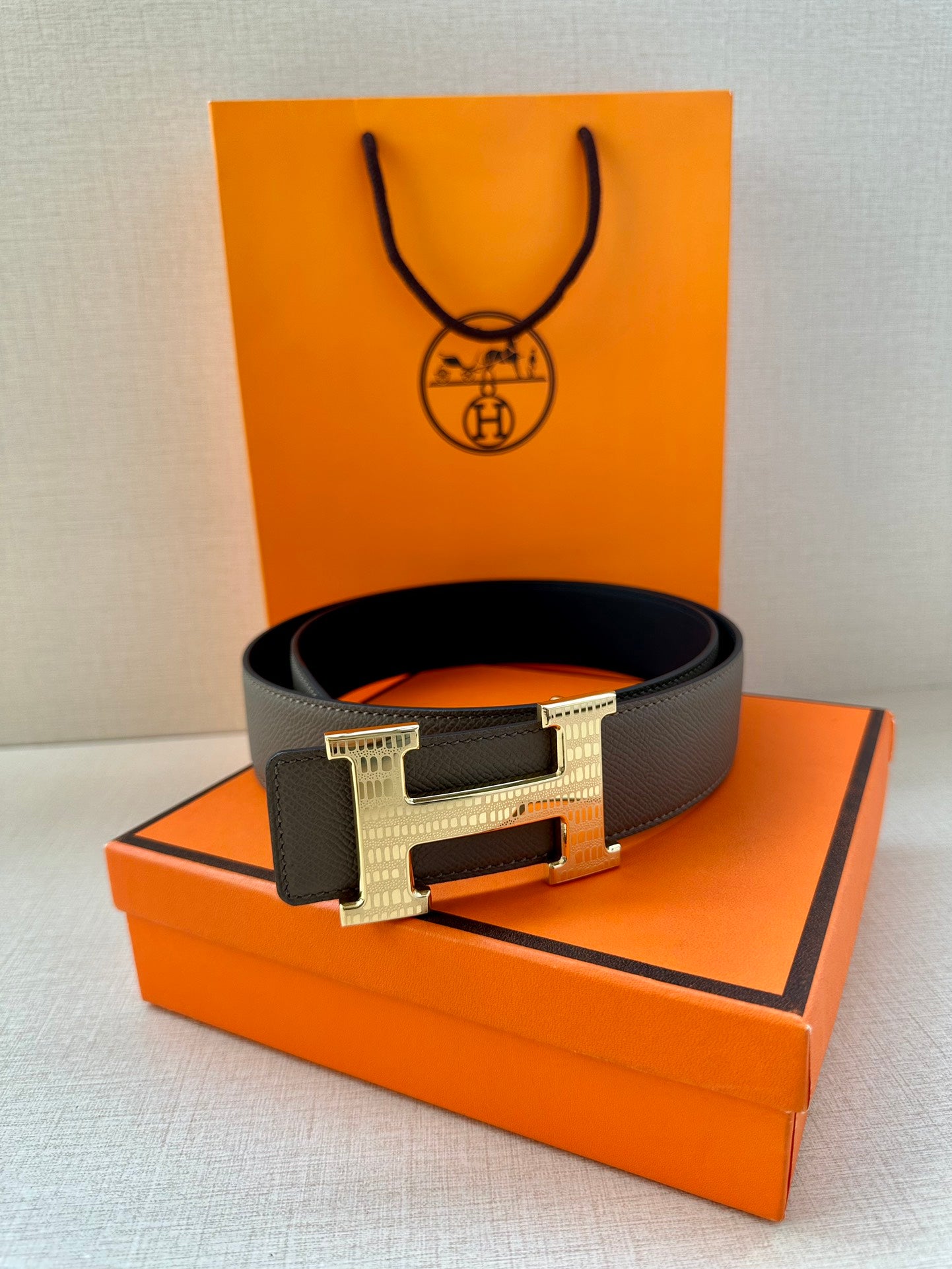 Gray leather belt with silver-tone H buckle, belt laid flat