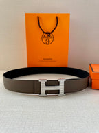 Gray leather belt with silver-tone H buckle, flat on surface