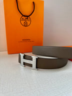 Gray leather belt with silver-tone H buckle, angled side view