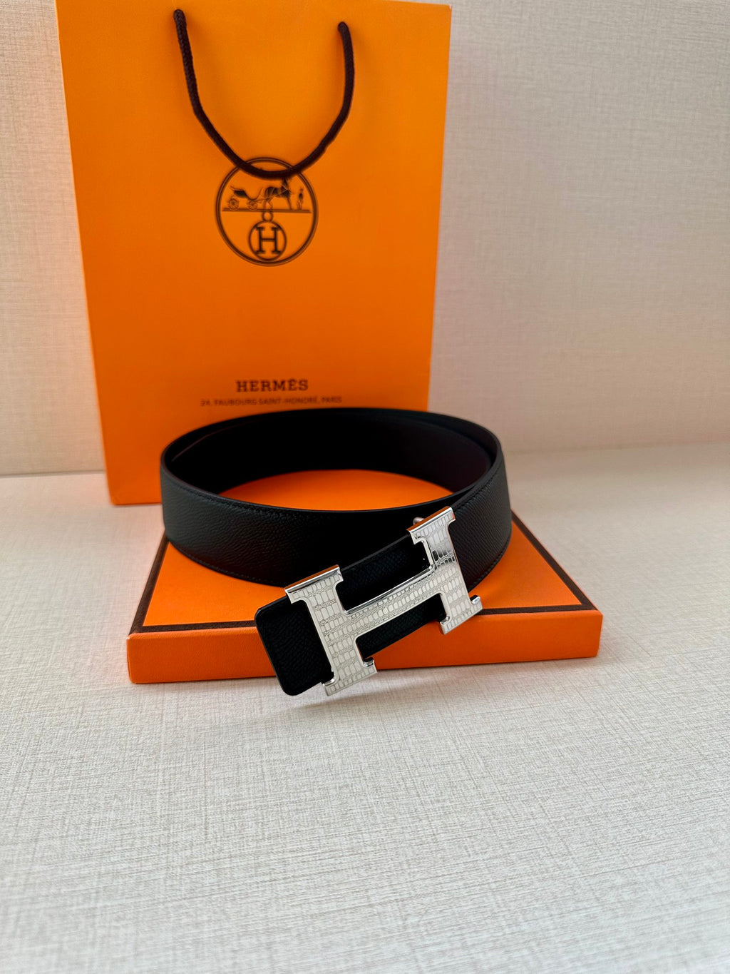 Black leather belt with silver-tone H buckle, flat on surface